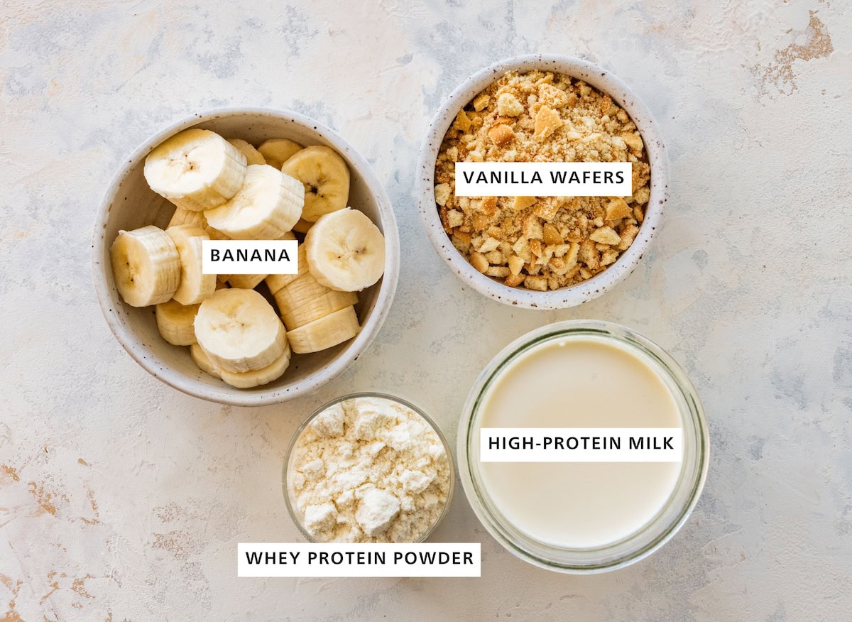 Ingredients measured out for high-protein banana pudding ice cream: banana, whey protein powder, high-protein milk, vanilla wafers.