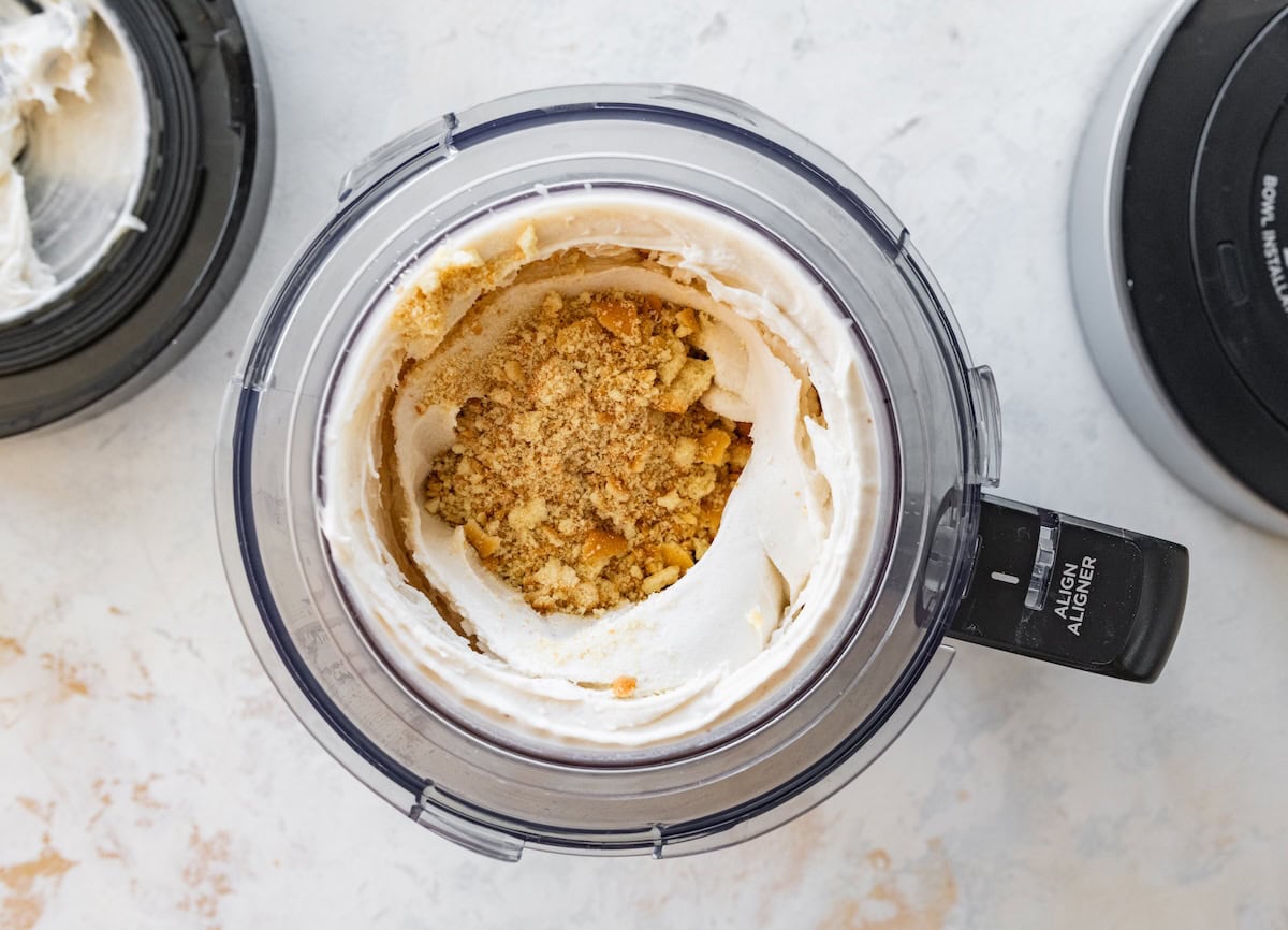 A ninja creami with a mix of banana, protein powder, milk, and vanilla wafers inside.