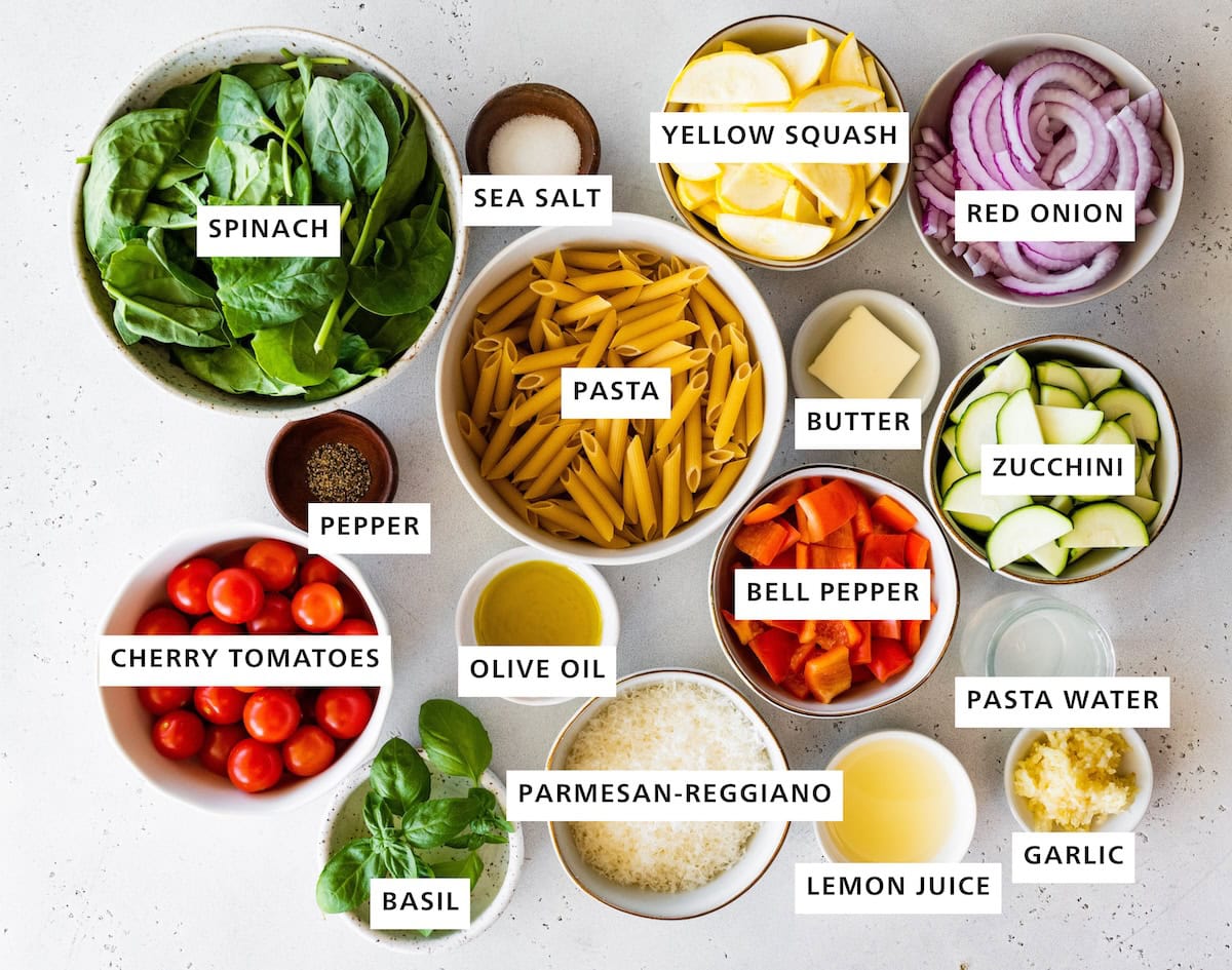 Ingredients measured out to make Pasta Primavara: cherry tomatoes, baby spinach, pepper, basil, olive oil, pasta, sea salt, parmesan-reggiano, bell pepper, butter, yellow squash, lemon juice, pasta water, garlic, zucchini and red onion.