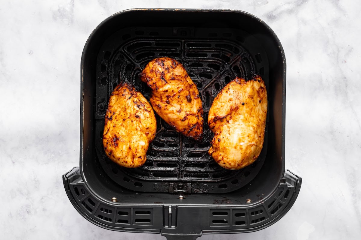 Cooked chicken in an air fryer basket.