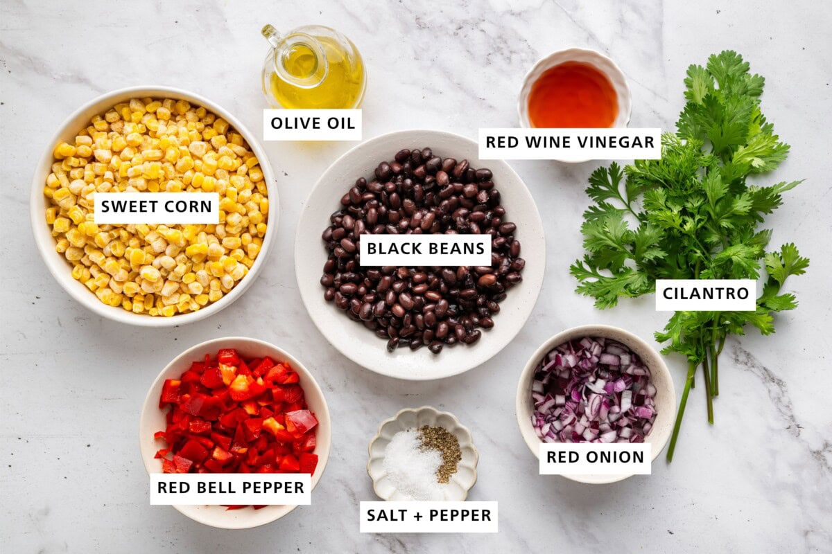 Ingredients measured out for black bean and corn salad: sweet corn, olive oil, red wine vinegar, cilantro, red onion, salt, pepper, red bell pepper, and black beans.