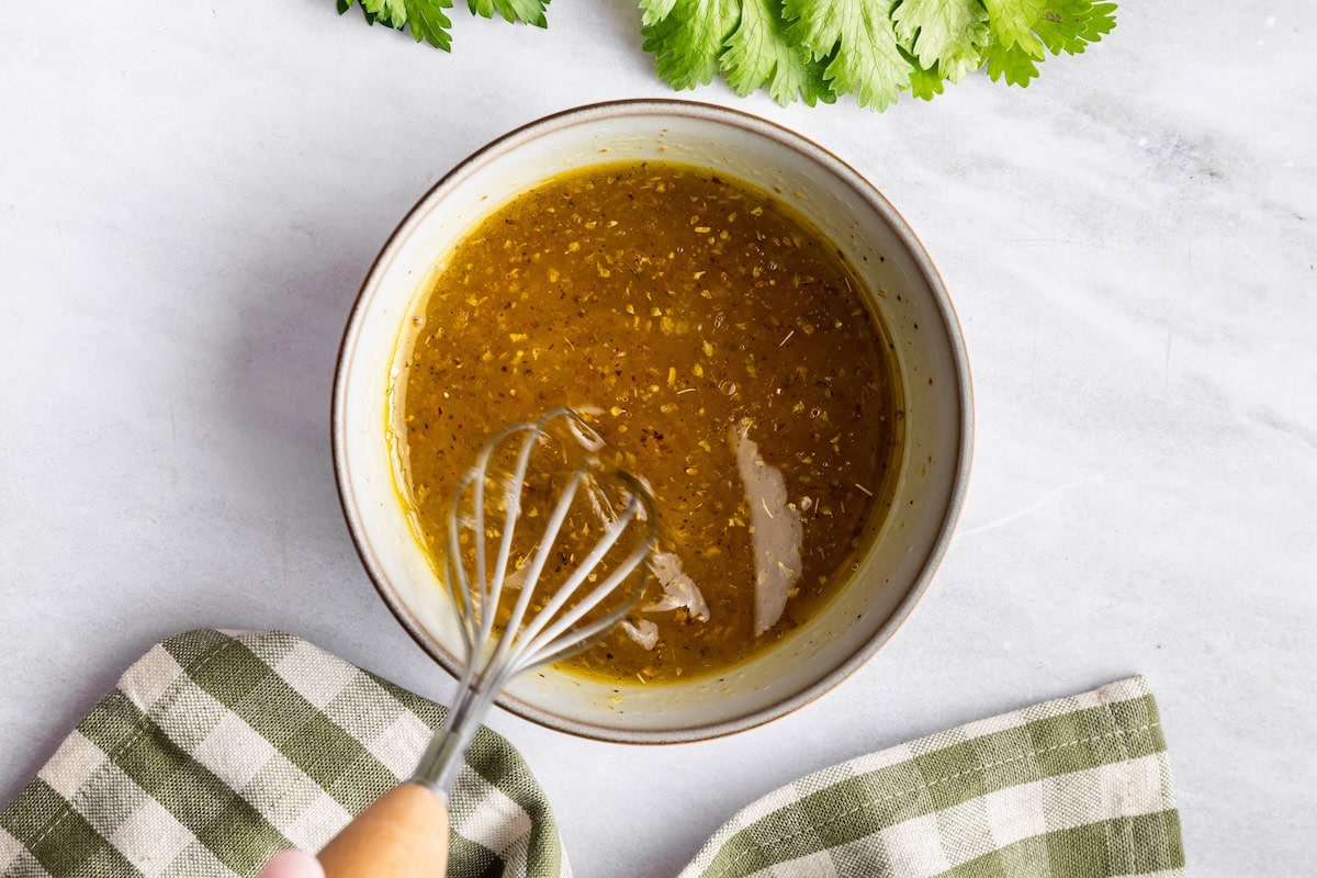 A dressing mixed with a whisk in a bowl.