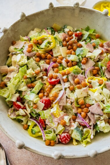 Grinder salad in a large serving bowl with chickpeas, veggies, and deli meats.