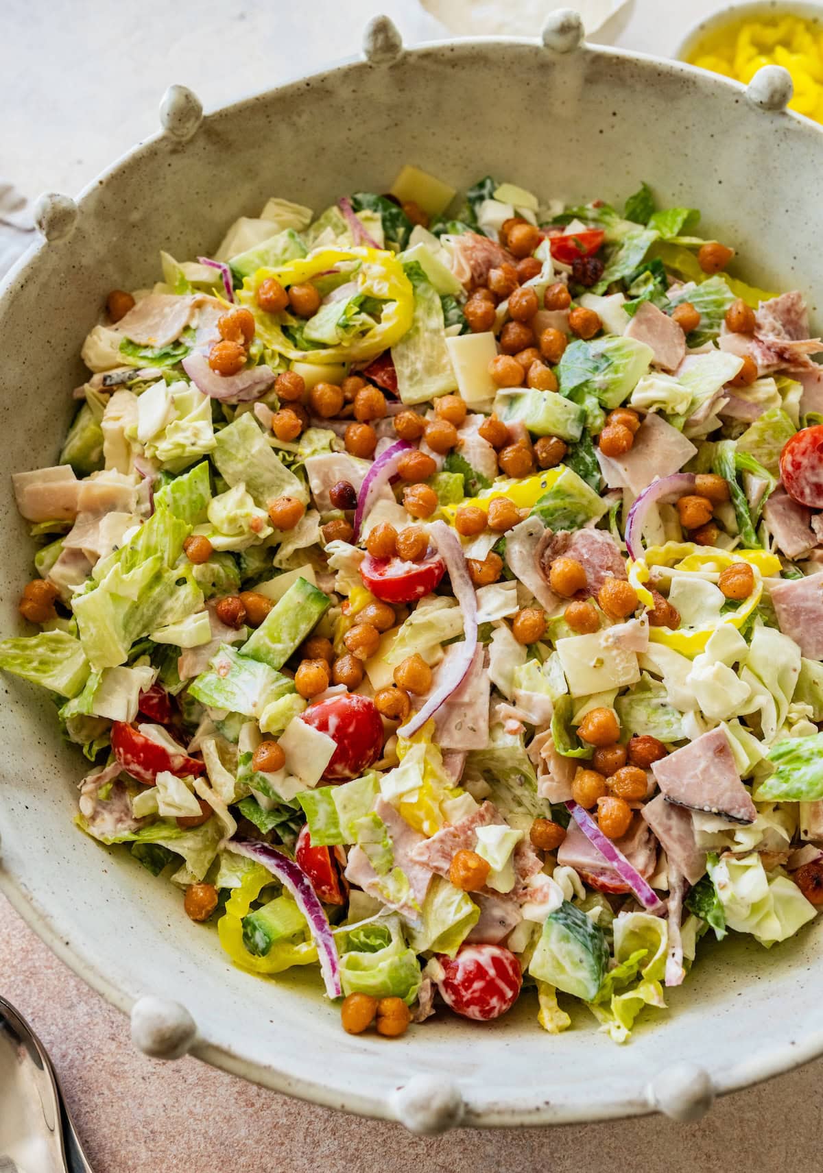 Grinder salad in a large serving bowl with chickpeas, veggies, and deli meats.