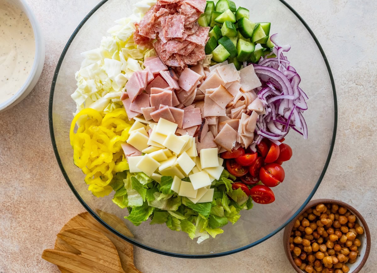 Grinder salad ingredients in a large glass bowl before being combined.