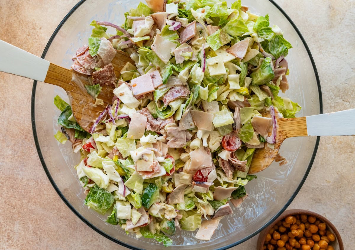 Grinder salad in a large glass bowl combined with a creamy dressing.