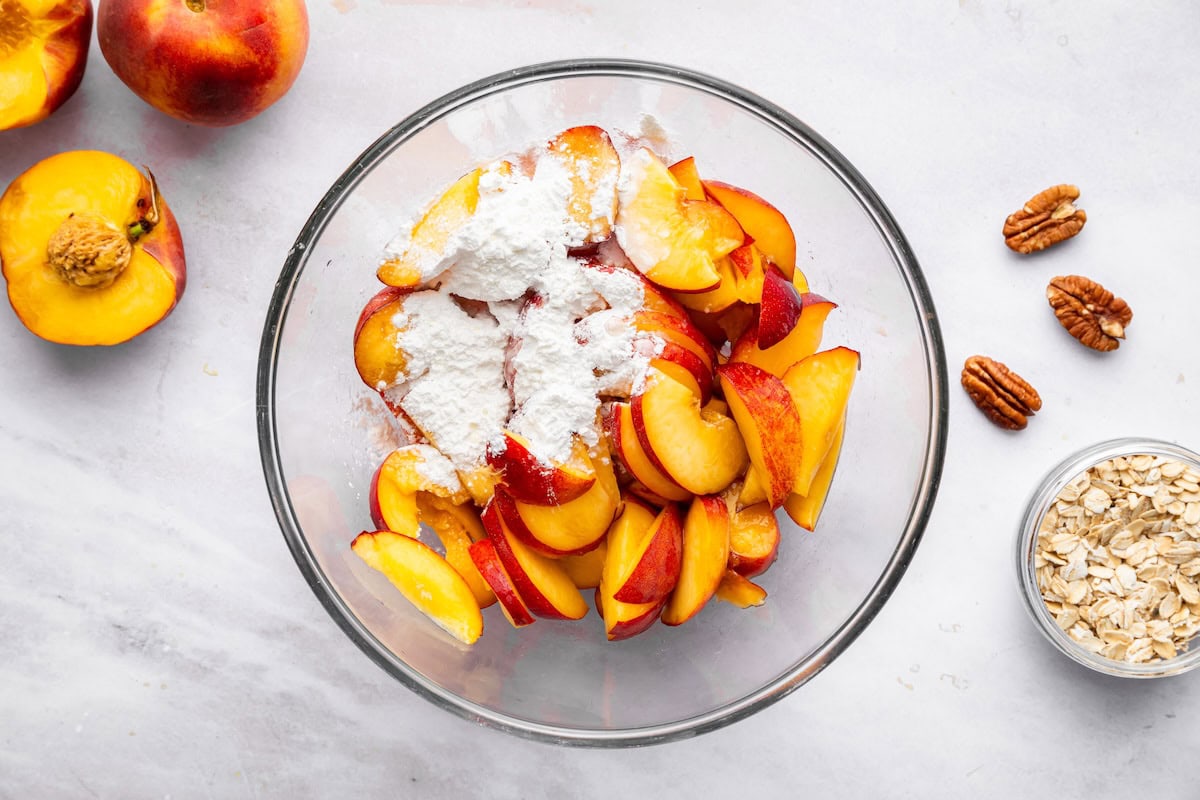 Fresh peaches with arrowroot powder in a large glass bowl.