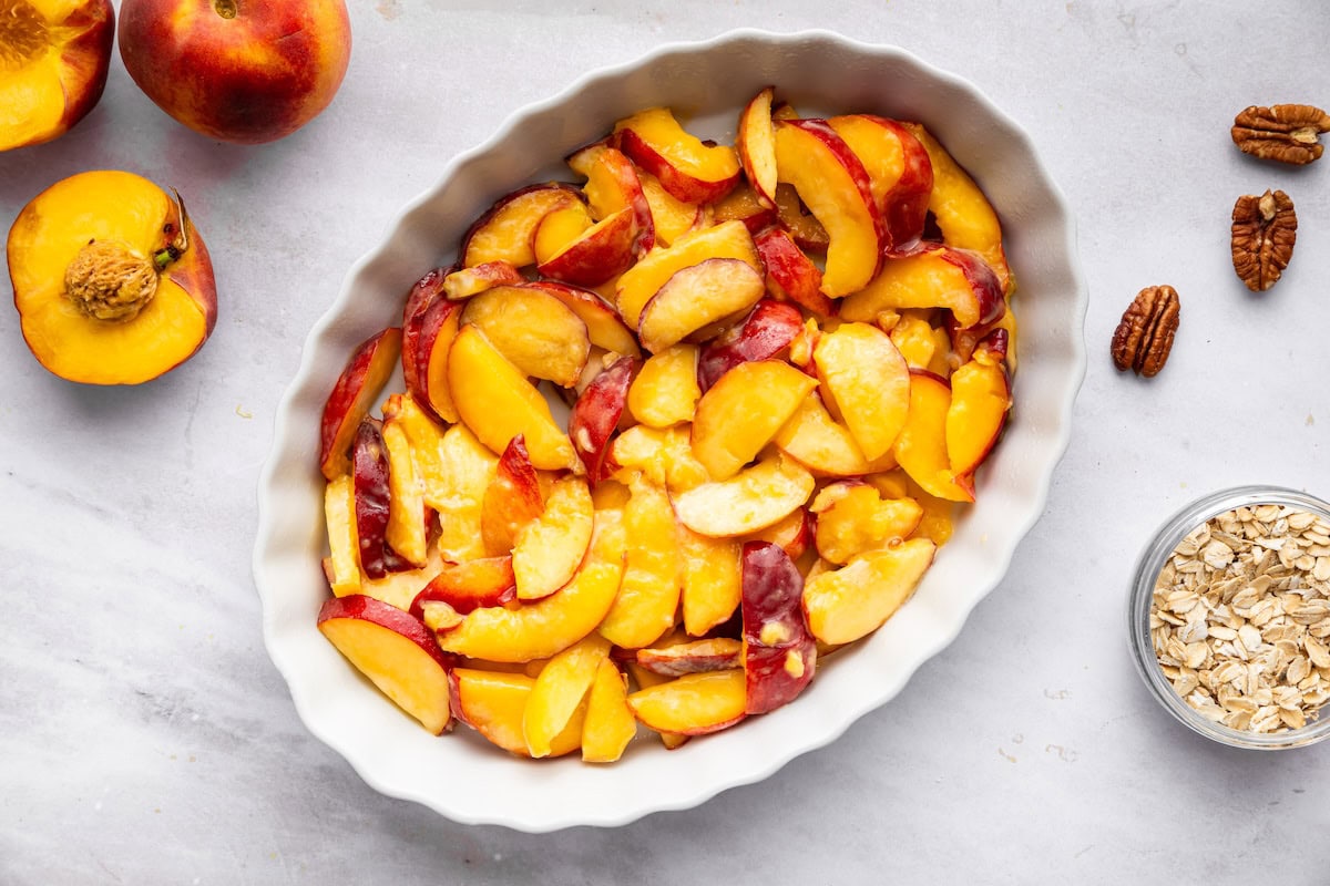 Baked peaches in a baking dish that will be used for a peach crisp.