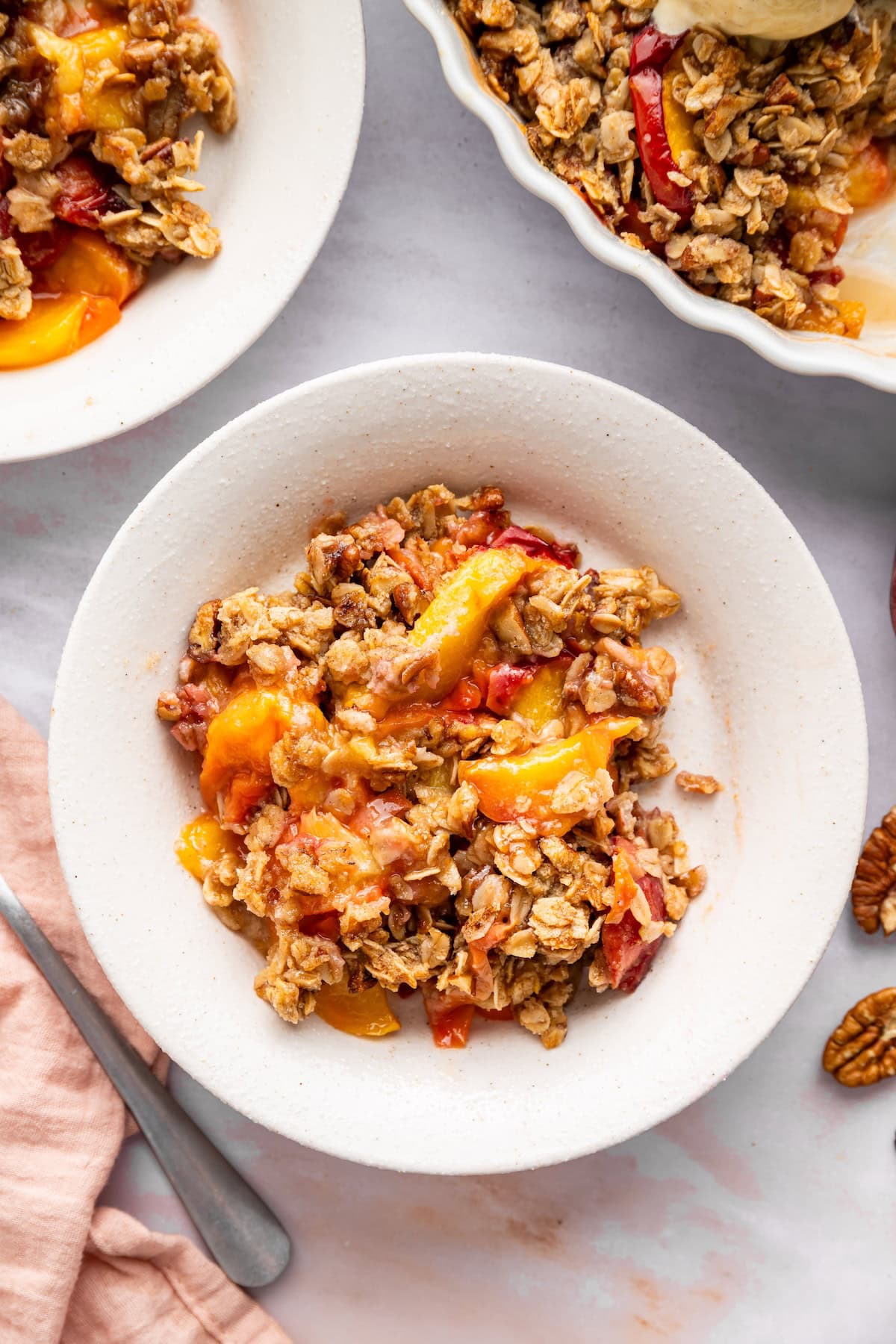 A serving of peach crisp in a white bowl.