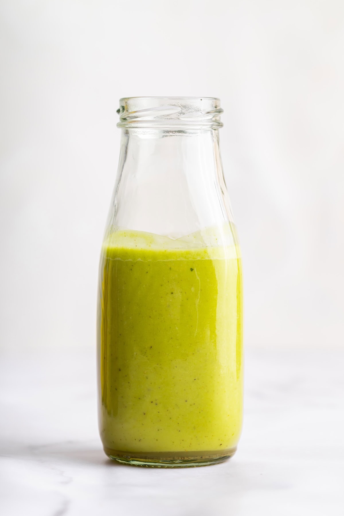 A cilantro lime dressing in a glass bottle.