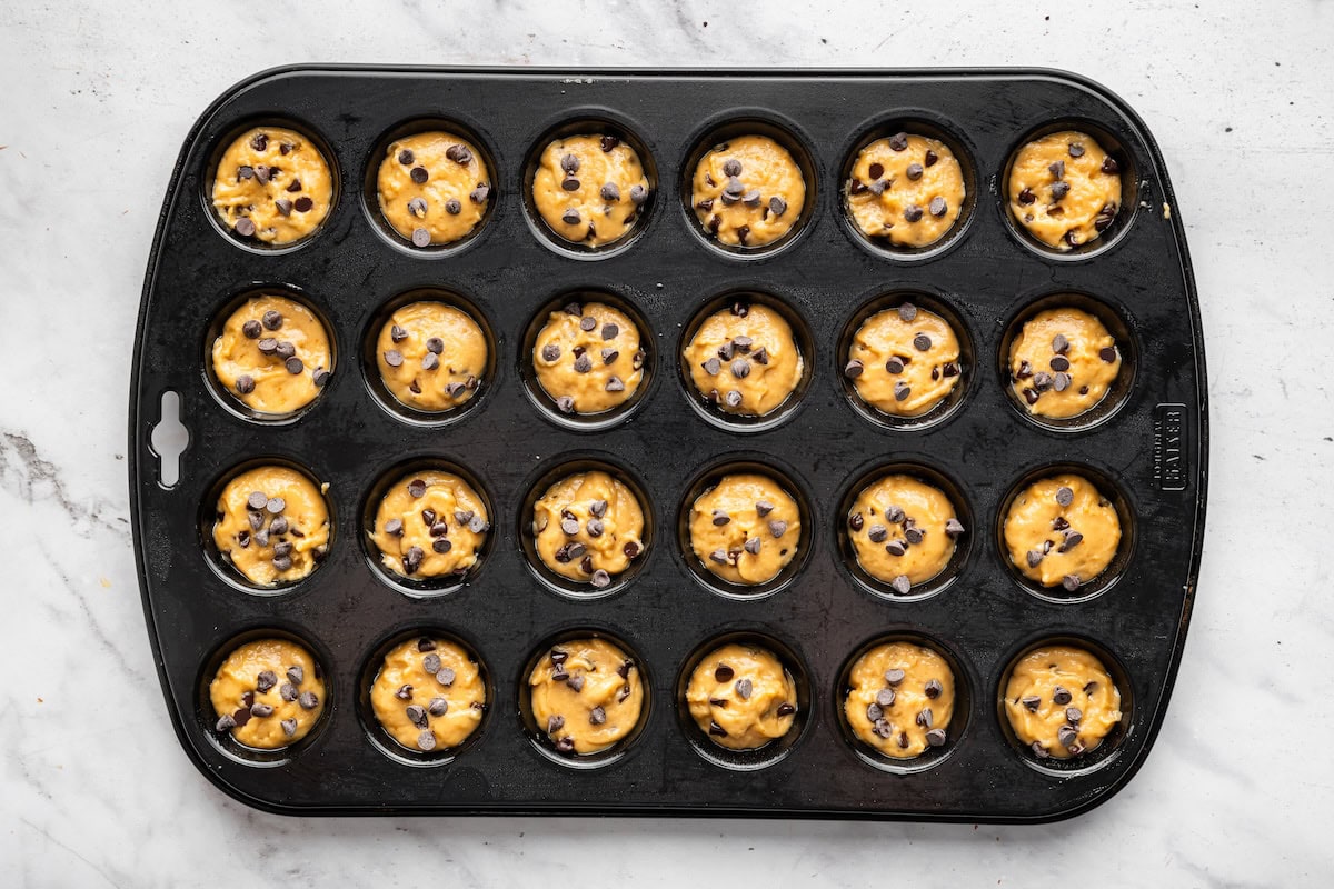 Mini chocolate chip muffin batter in a muffin tin.