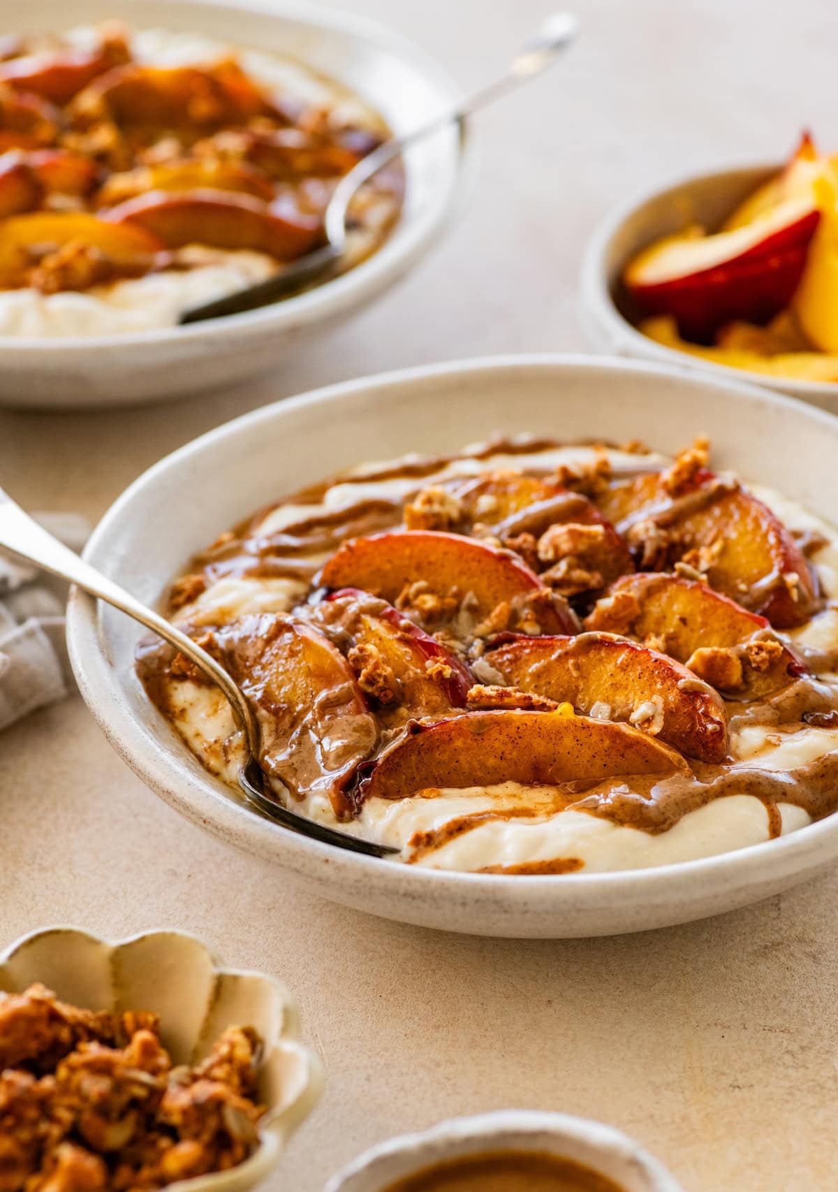 A serving of a high protein peach crisp yogurt bowl topped with caramelized peaches and a drizzle of almond butter.
