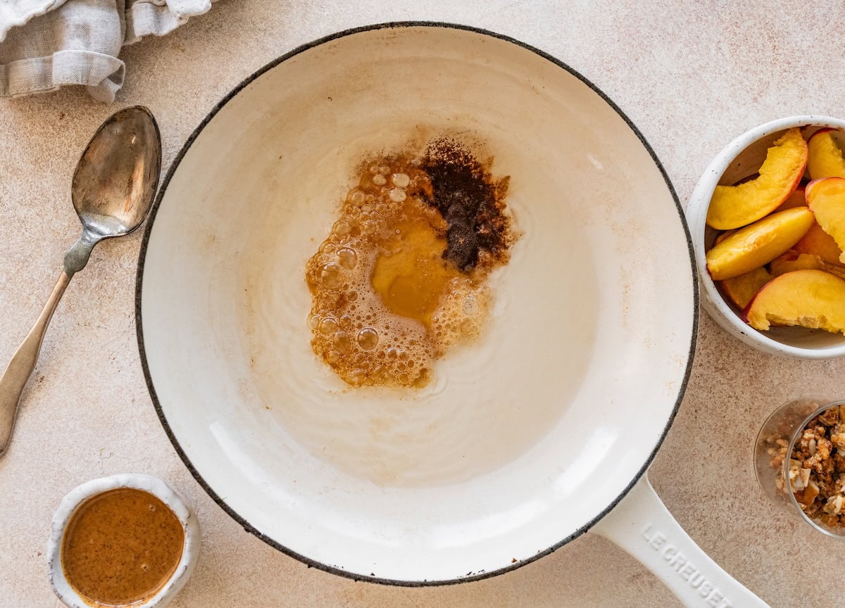 Maple syrup heating up in a white skillet.