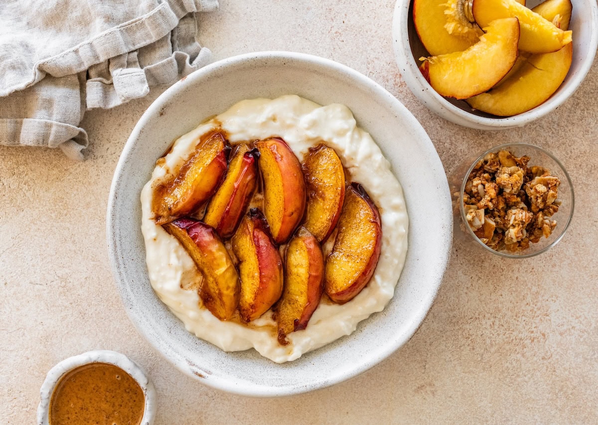 Peach slices topped in a bowl with greek yogurt and cottage cheese with protein powder.