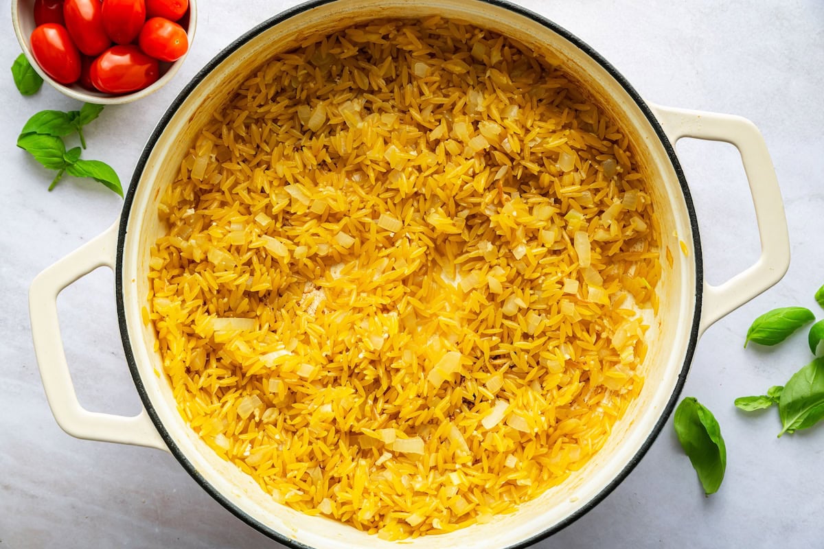 Orzo added to a large pot with sauteed onion.