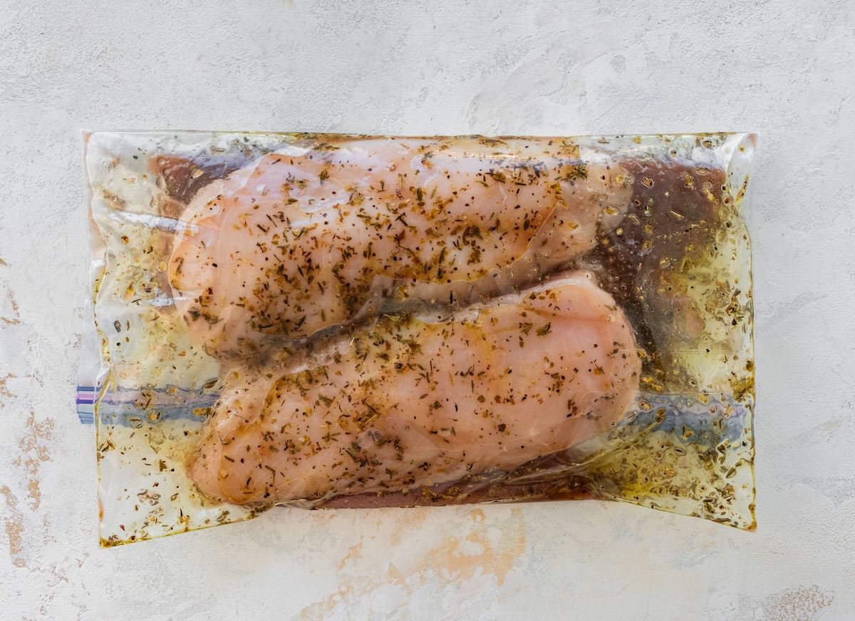 Raw chicken marinating in a plastic bag.