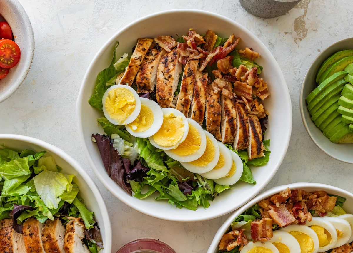 Chicken cobb salad with hard boiled egg served in a bowl.