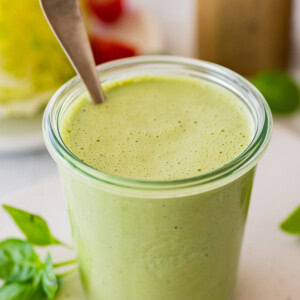 Green goddess dressing in a glass weck jar with a spoon in it.