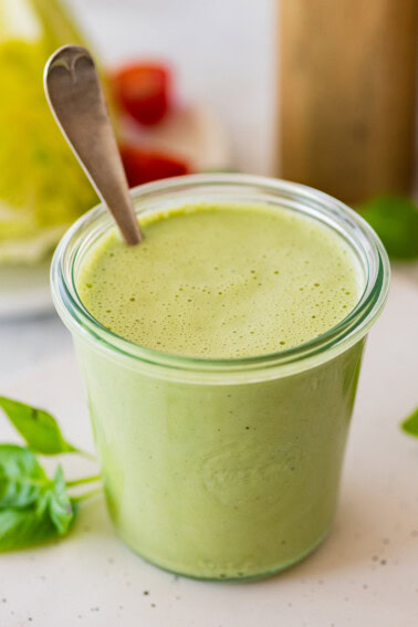 Green goddess dressing in a glass weck jar with a spoon in it.