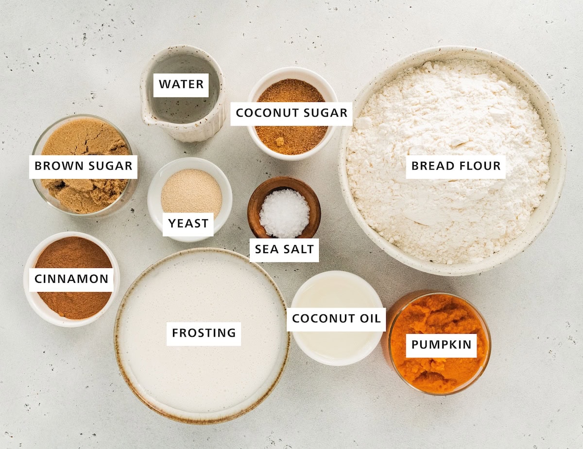 Ingredients measured out to make Vegan Pumpkin Cinnamon Rolls: bread flour, pumpkin, coconut oil, coconut sugar, sea salt, frosting, yeast, water, brown sugar and cinnamon.