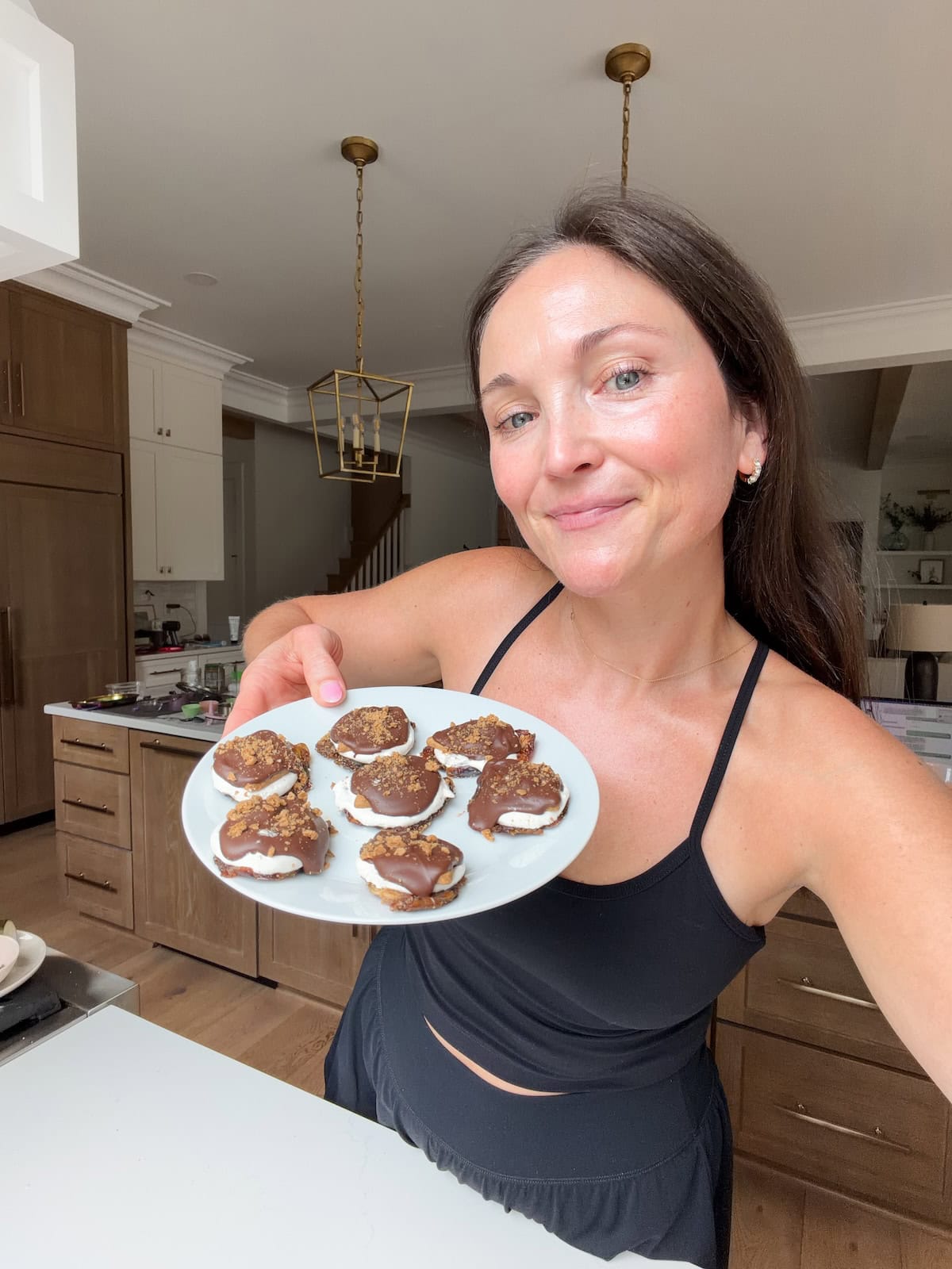 Brittany smiling and holding a white plate with smashed date s'mores.