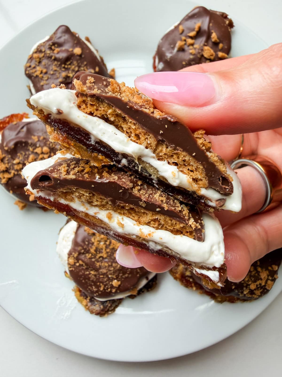 A smashed date s'mores cut in half where you can see the layers of the medjool date, graham cracker and marshmallow fluff.