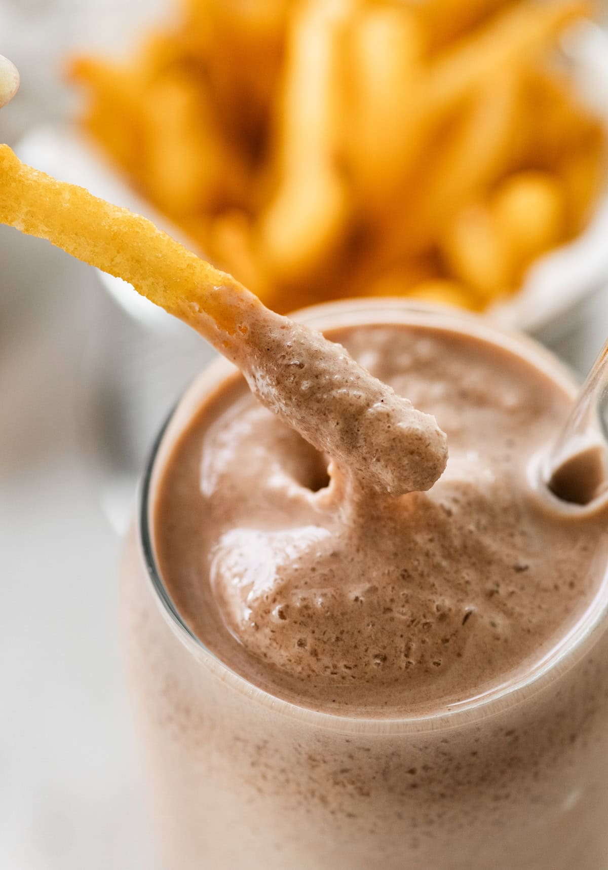 A french fry being dipped into a chocolate Wendy's copycat chocolate frosty.
