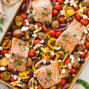A salmon sheet pan meal on a sheet pan with four salmon filets and roasted veggies.