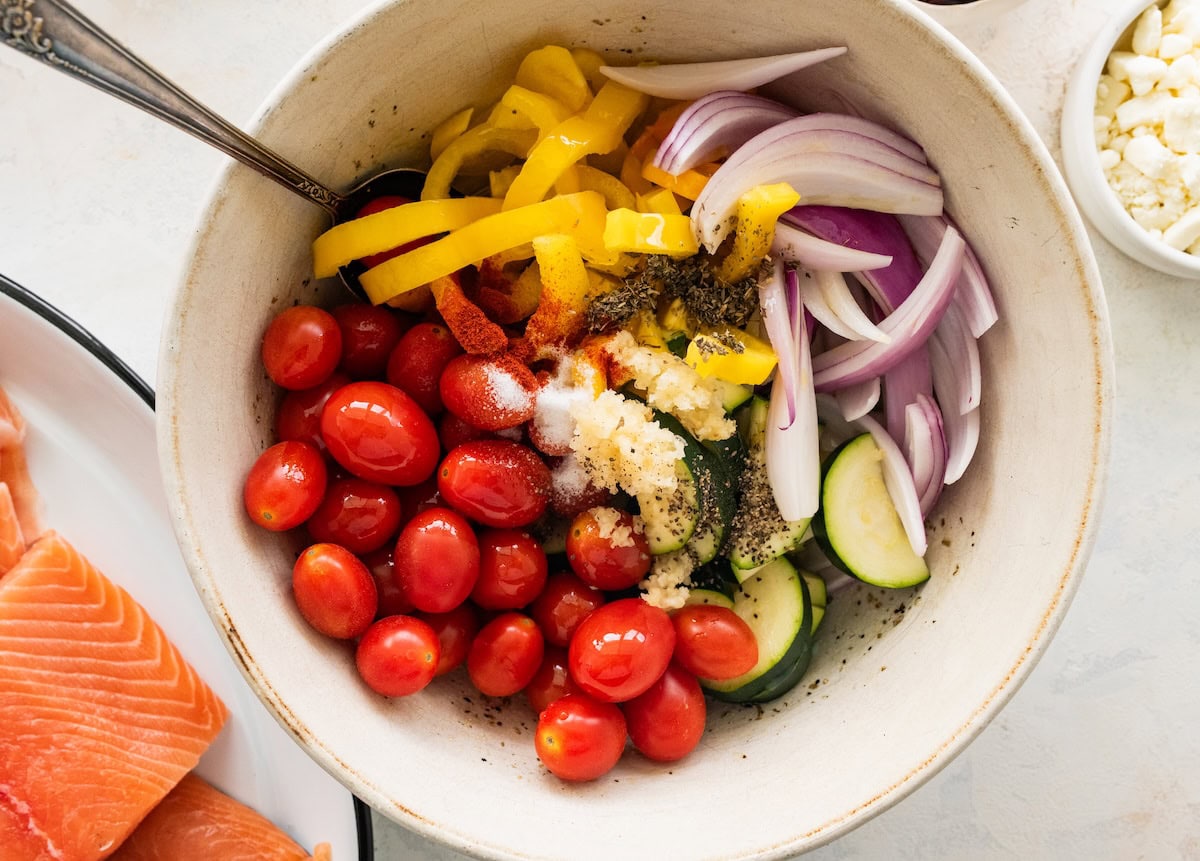 Fresh vegetables in a large mixing bowl with garlic, salt, and pepper.